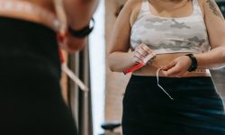 woman measuring waist with tape in gym