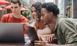 amici giovani e diversi felici fanno i compiti in un bar usando i netbook