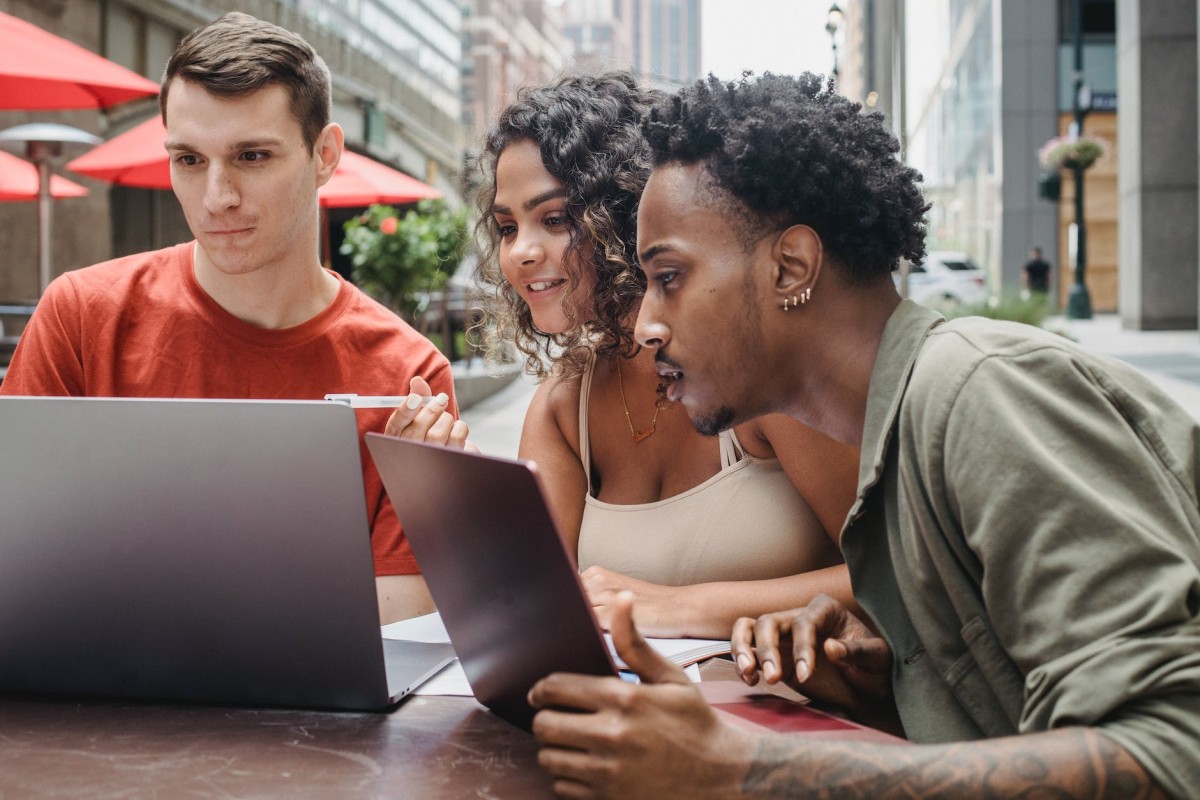 heureux jeunes amis divers faisant leurs devoirs dans un café à l'aide de netbooks