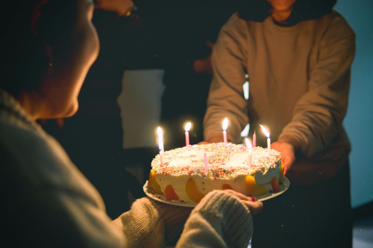 dos personas sosteniendo pastel con velas encendidas