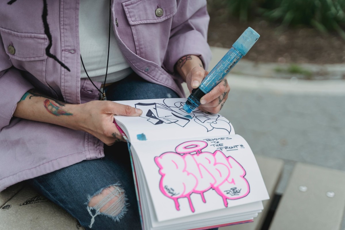 Unerkennbare Frau, die Graffiti auf Papier zeichnet